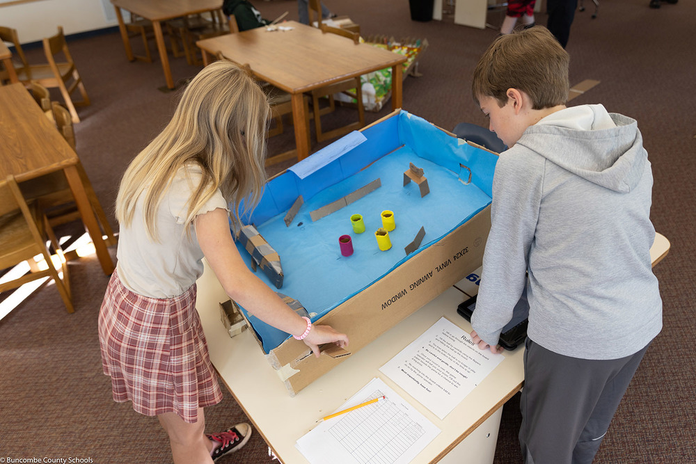 A female student playing a cardboard version of pinball