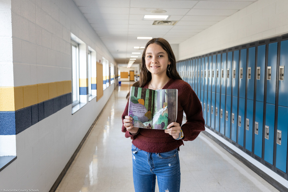 Valley Kitt holds her book in the school hallway.