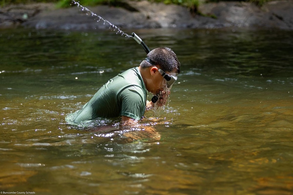 A student blows water out of a snorkel