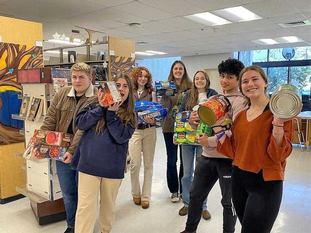 photo of students posing in school library with food donations