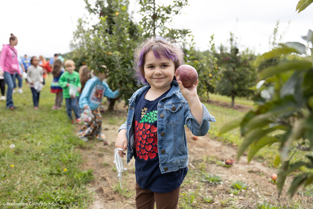 Student holding up an apple that she picked. 