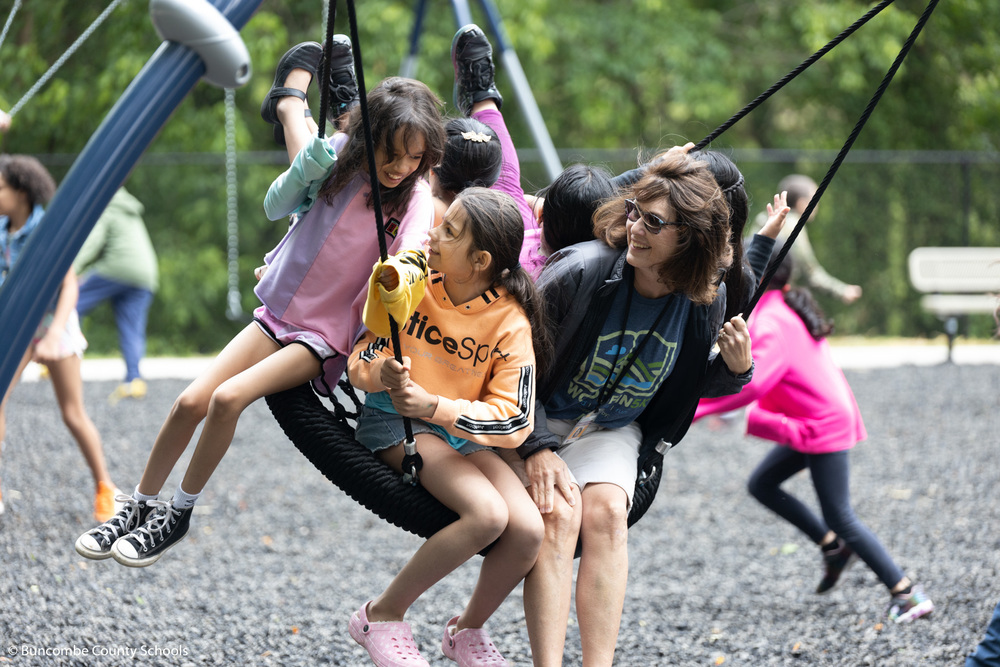 Students and staff swinging on the new saucer swing. 