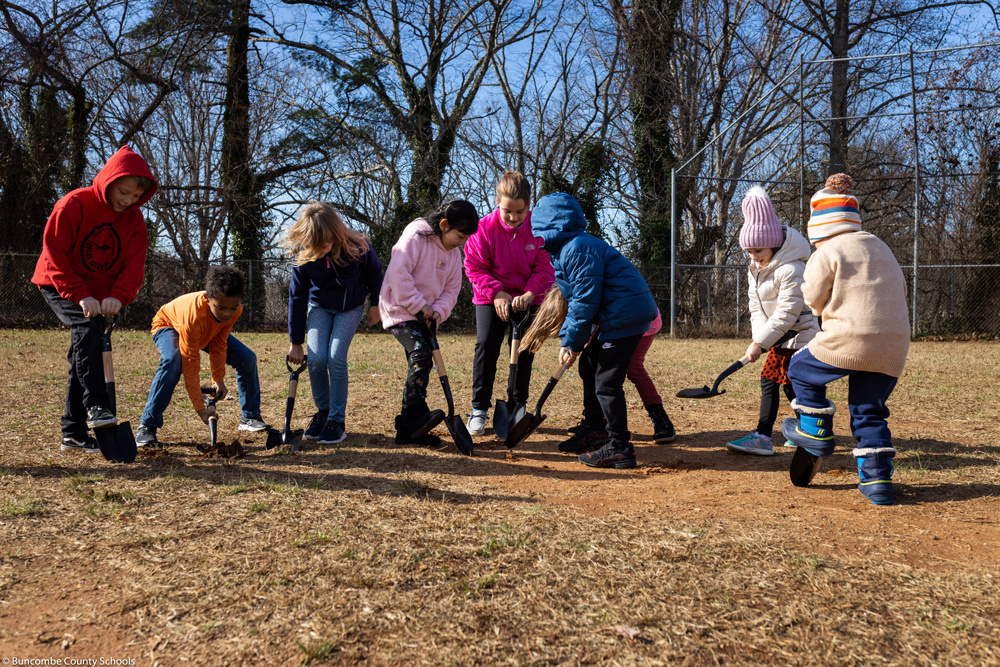 Students dig with small shovels.
