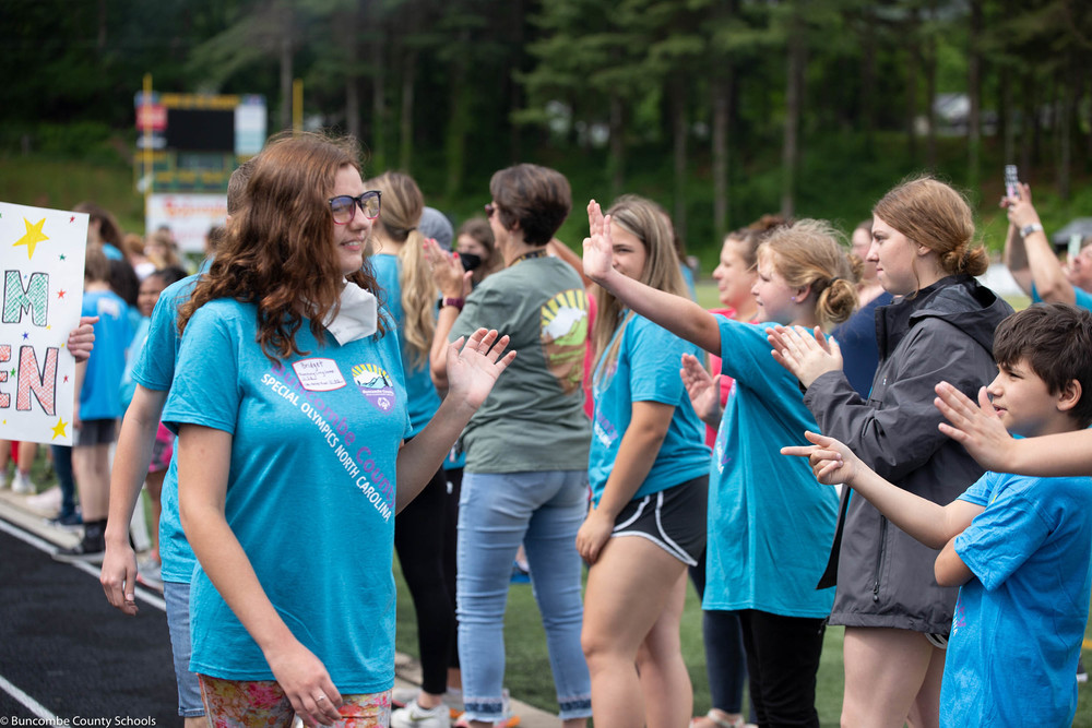 Student participating in special olympics waving at people on the sidelines. 