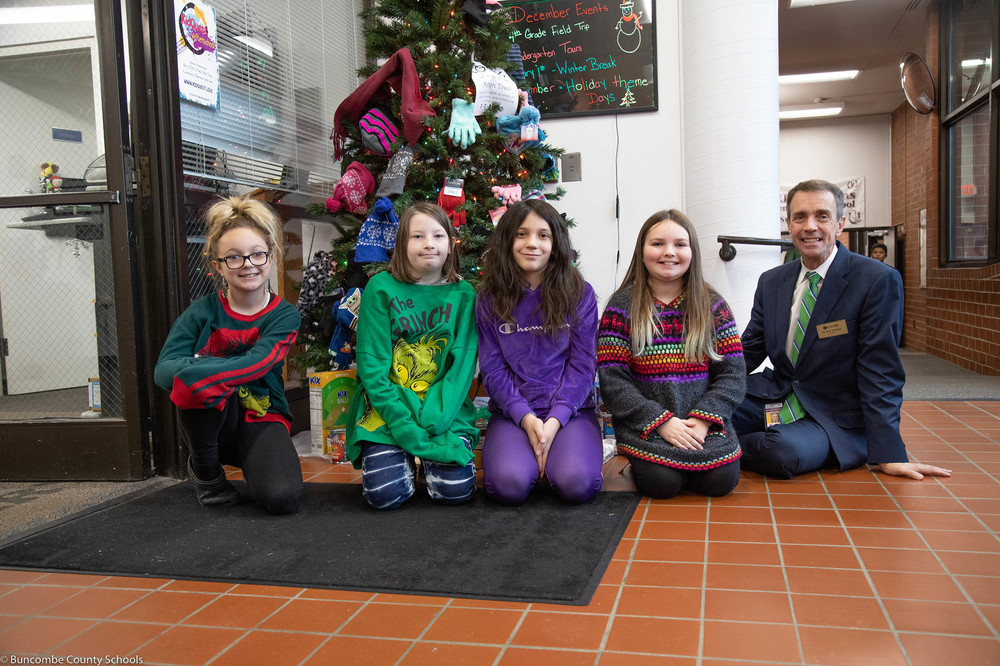Dr. Jackson sitting in front of the mitten tree with members of the K-Kids Club.