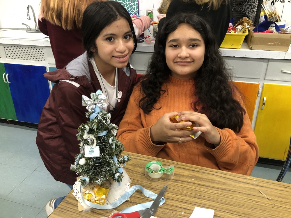 Two students work on a small Christmas tree