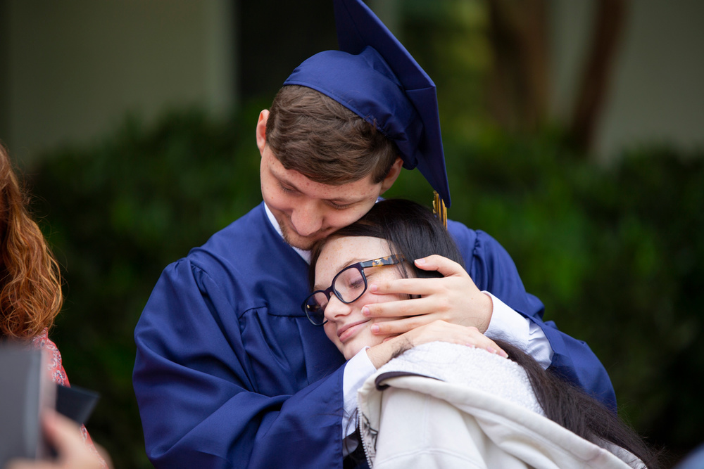 A graduate hugging another person.