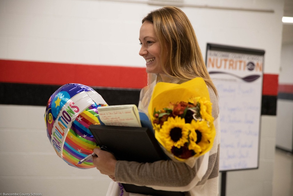 principal smiles with bouquet of sunflowers and a balloon