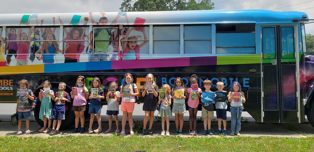 Students holding books outside of book mobile