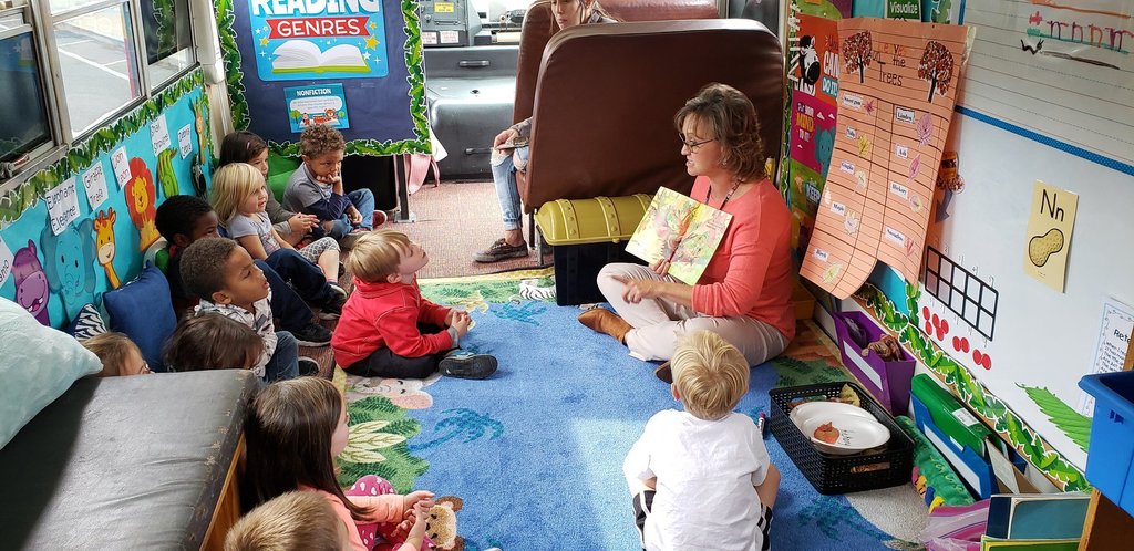 teacher reads to children inside school bus redesigned to be a classroom library