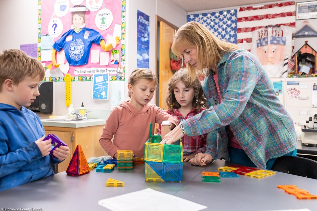 teacher helps students build with magnetic blocks