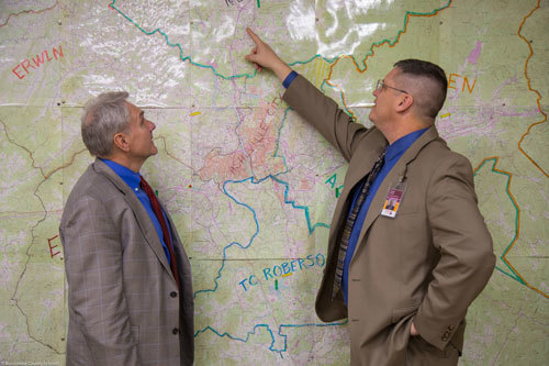 A man pointing at a map while another man looks at the map