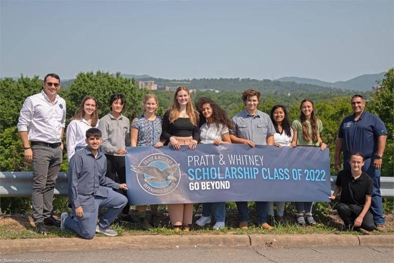 A group of students holding a scholarship banner