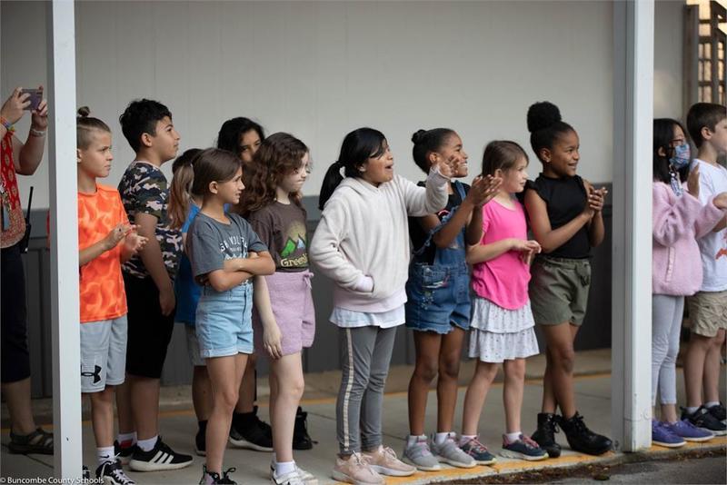 Students lined up in front of the school smiling