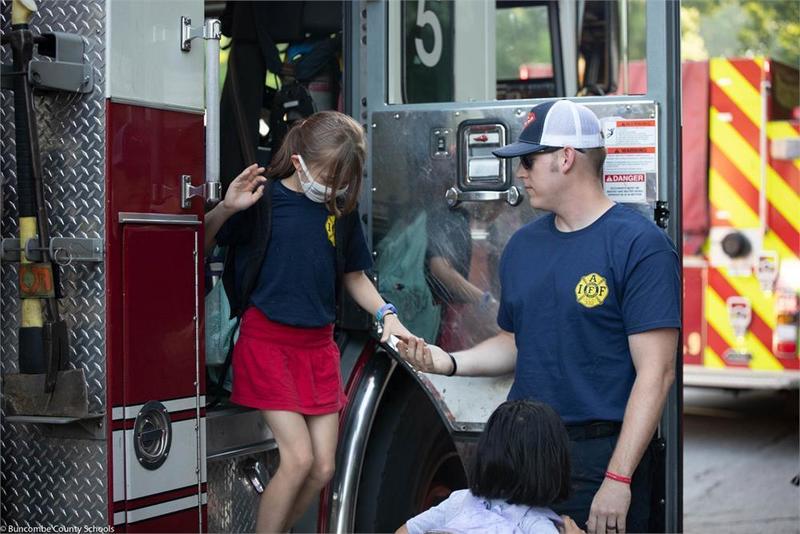 Fire fighter helping a student down from a fire truck