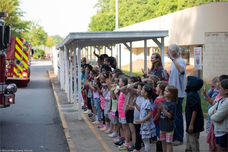 Students lined up in front of school waving at fire truck