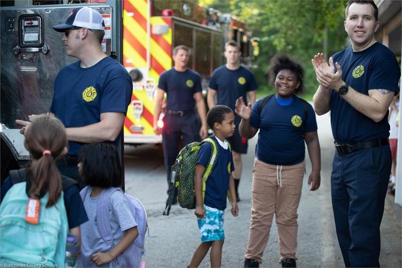Students and fire fighters standing by a fire truck