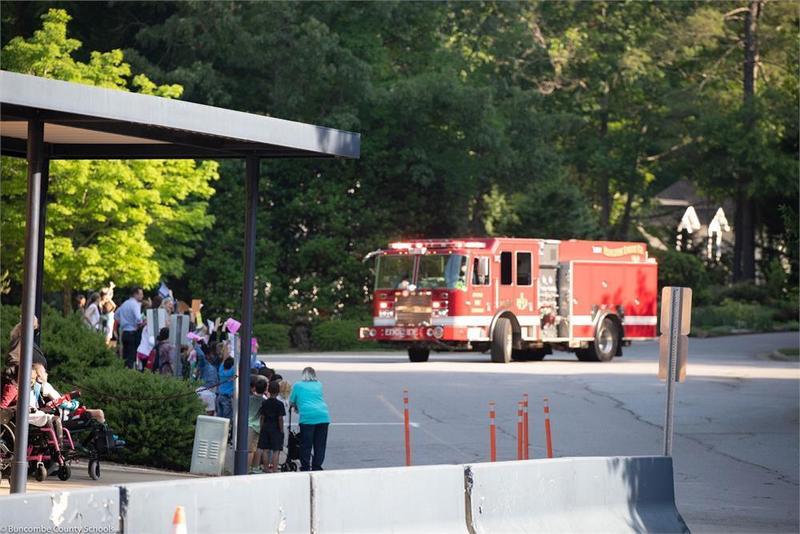 Fire truck pulling up in front of school with students lined up outside