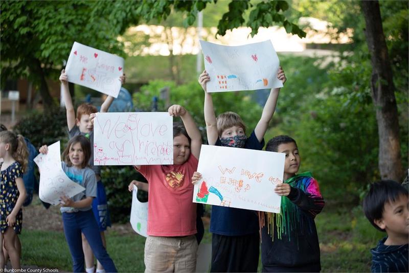 Students holding up hand drawn posters