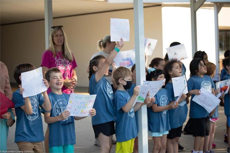 Students holding hand drawn signs in front of school