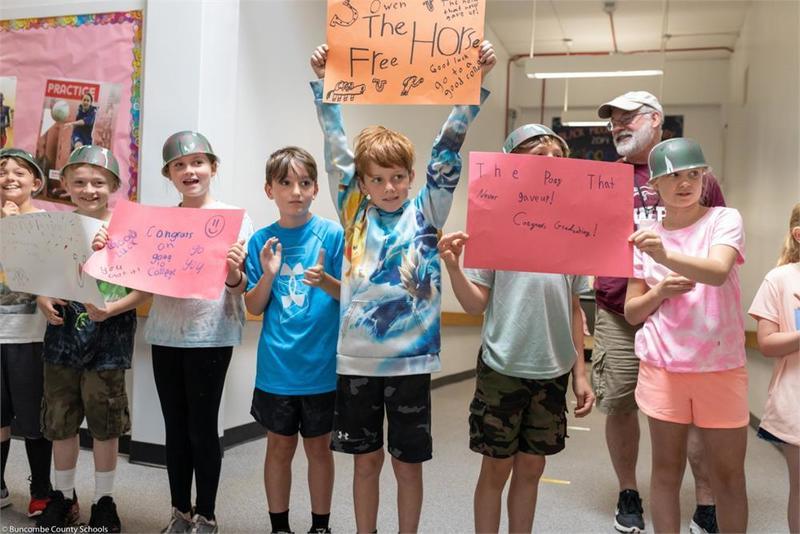 Young students holding handmade signs lined up in the hall
