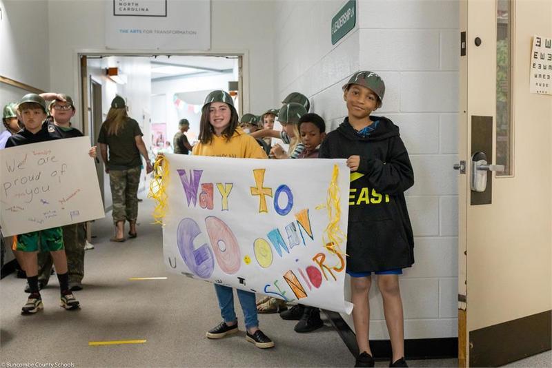Upper elementary holding handmade signs in the hall