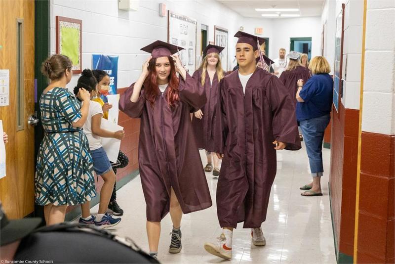 Graduates walking down the hall past students
