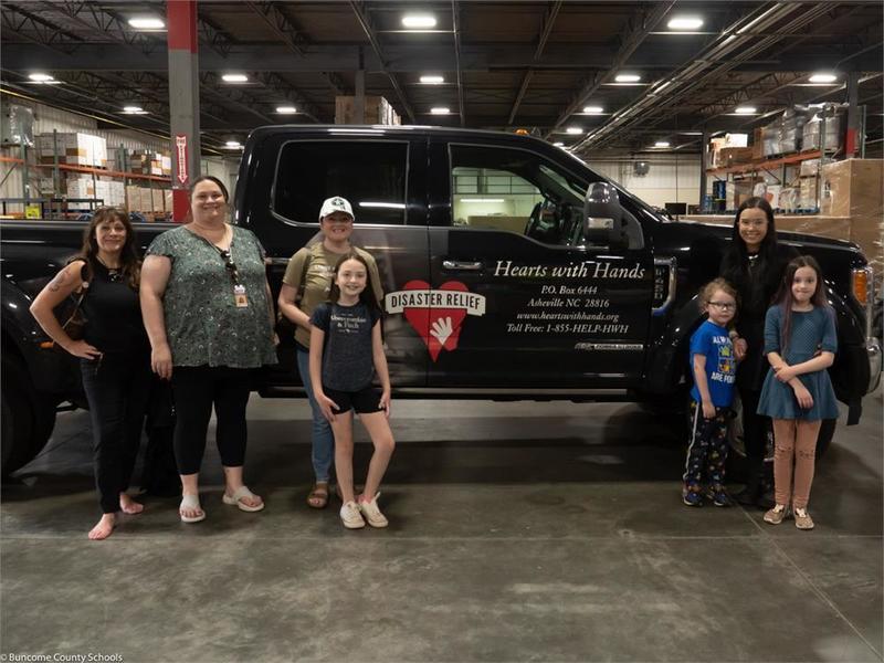 Donating students pose with hearts with hands truck