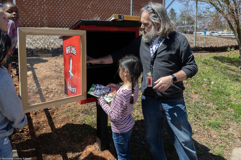 Girl puts books into Little Library