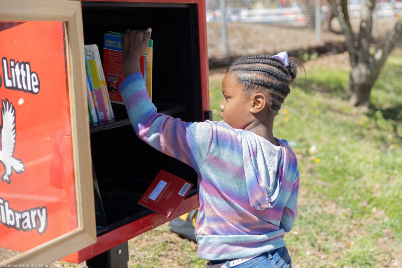 girl puts books into Little Library