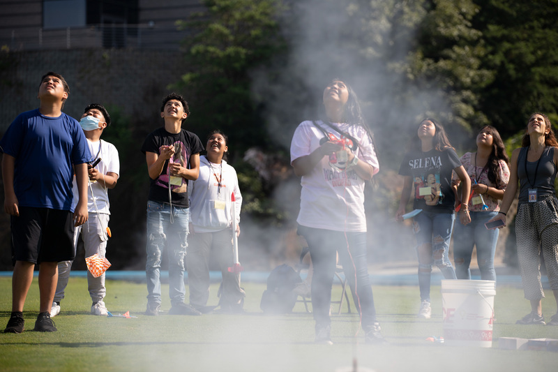 Rocket being launched and students watching to see how far it goes. 