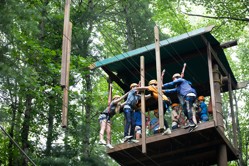 Students tackling the ropes course in a team of four.