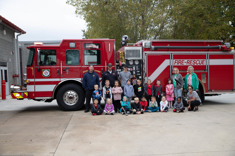 A group of students and firefighters in front of one of the trucks.