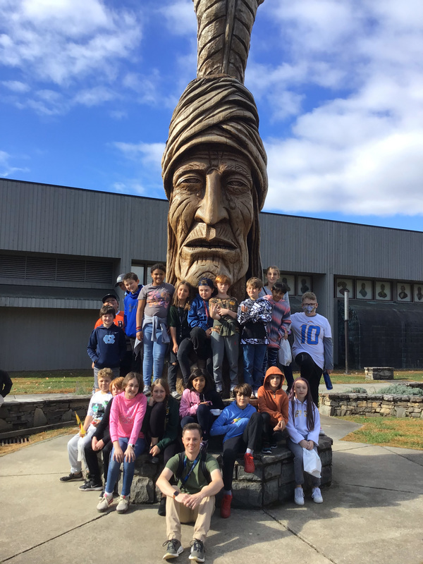 Fifth graders standing in front of a statue in Cherokee.