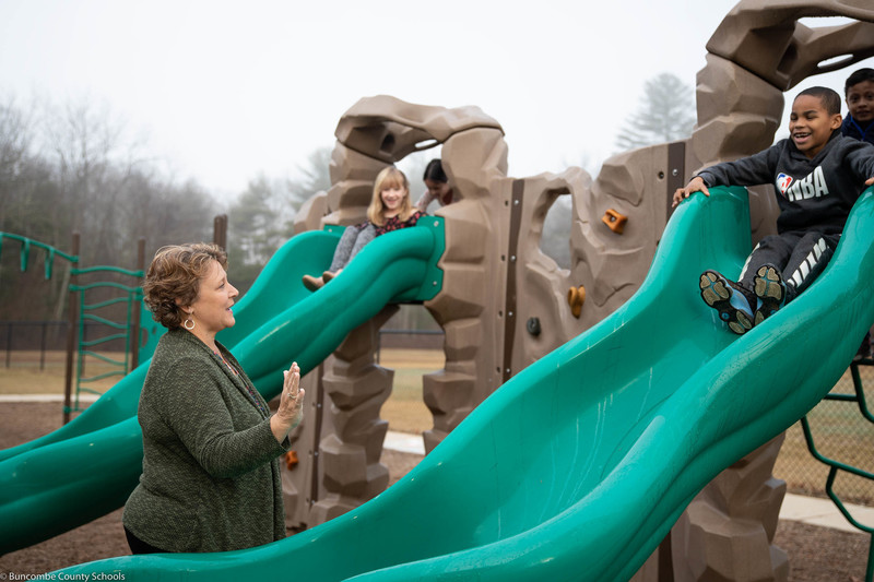Ms. Kertesz giving a student a high five as they come down the slide. 