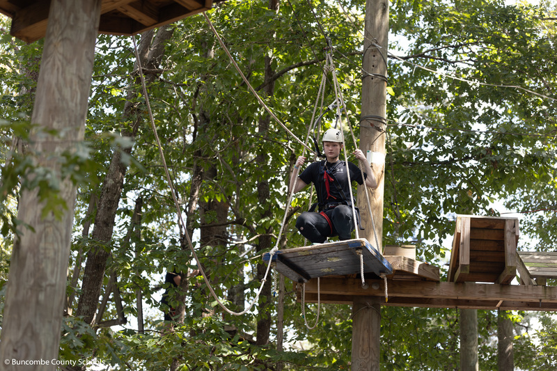 Student trying to accomplish the high ropes course at the Asheville Adventure Center.